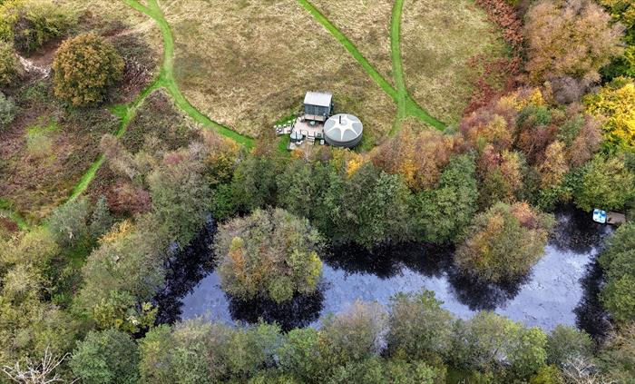 The yurt is situated at the bottom of the meadow, behind a small lake fringed with trees.